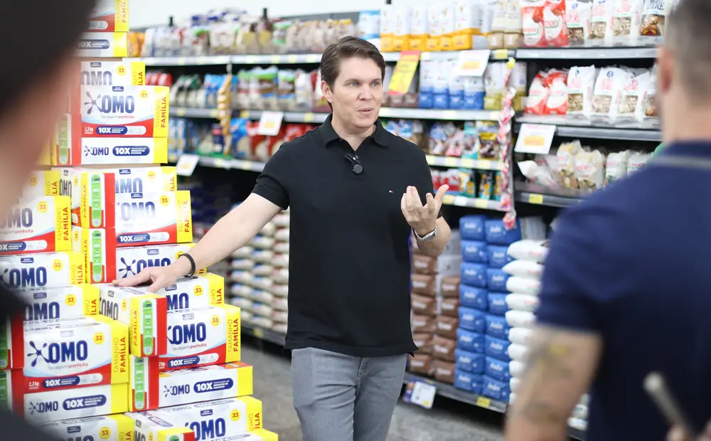 Pedro Della'Nora explicando estratégias para donos de supermercado no corredor de um supermercado